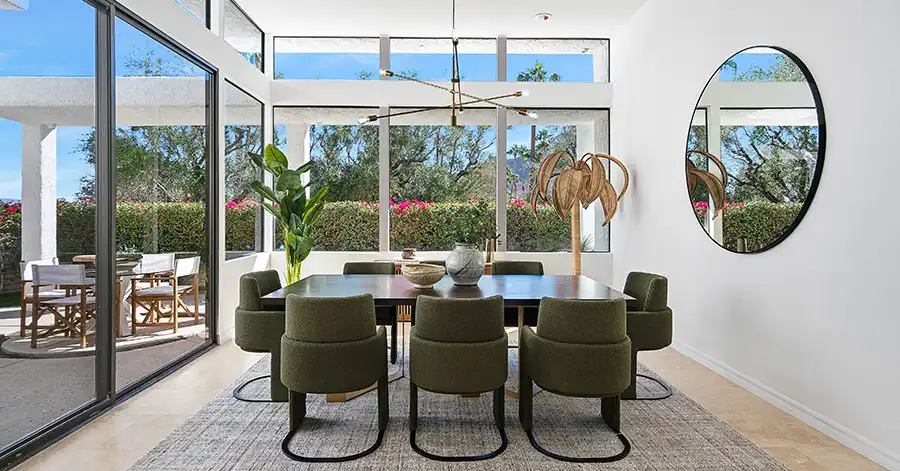 Dining room room in Mid-century modern home surrounded by two walls of glass windows and doors